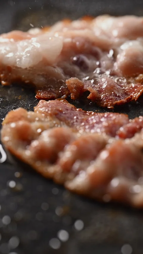 Crispy bacon sizzling in a pan, close-up shot. 動画素材 317452848