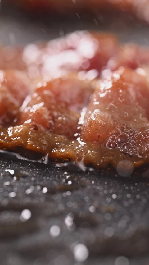 Crispy bacon sizzling in a pan, close-up shot. 動画素材 317452877