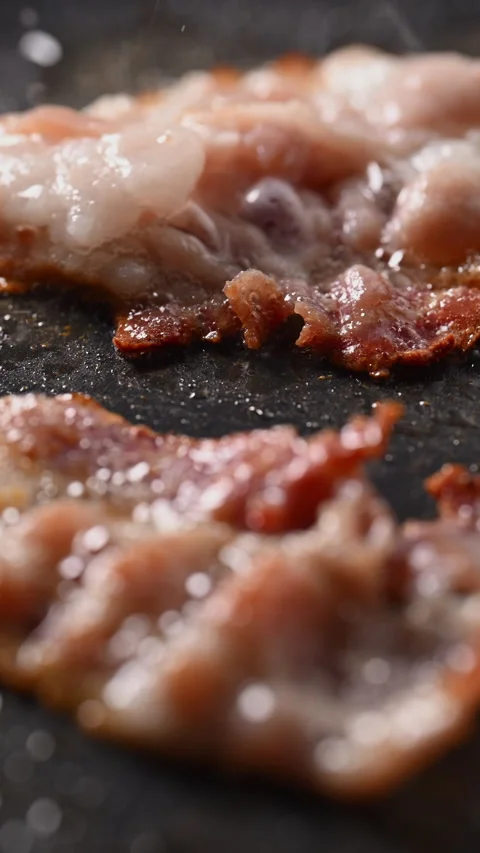 Crispy bacon sizzling in a pan, close-up shot. 動画素材 317452900