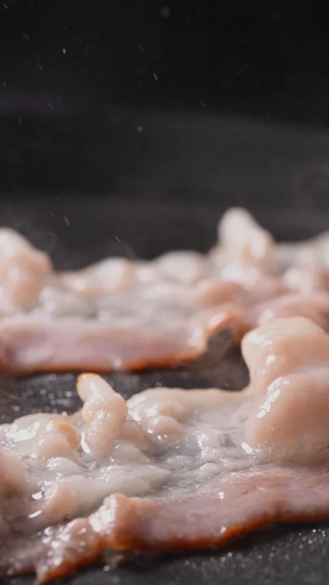 Crispy bacon sizzling in a pan, close-up shot. 動画素材 317453126
