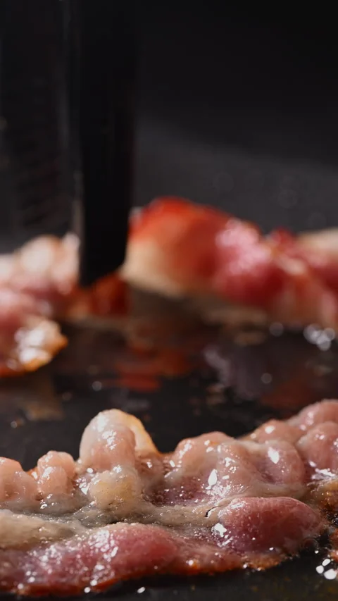 Crispy bacon sizzling in a pan, close-up shot. 動画素材 317453184