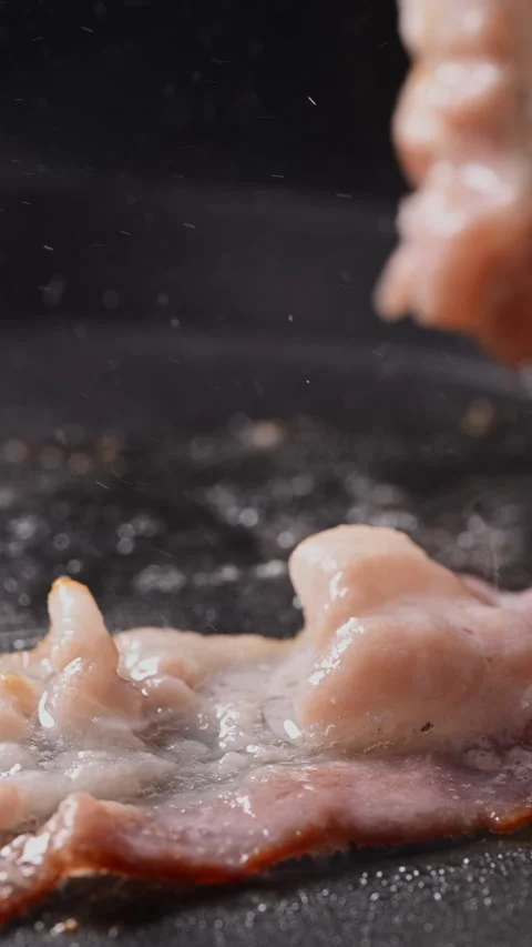 Crispy bacon sizzling in a pan, close-up shot. 動画素材 317453202
