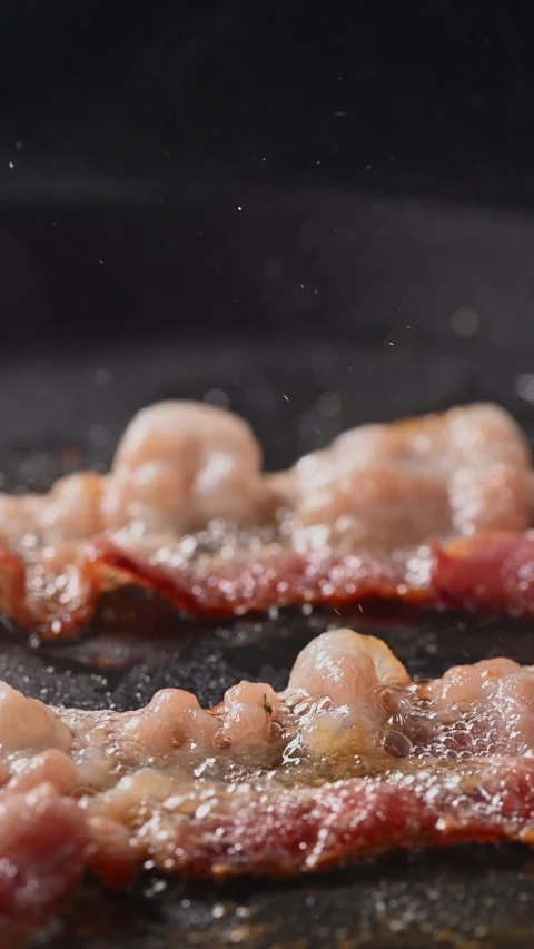 Crispy bacon sizzling in a pan, close-up shot. 動画素材 317453329