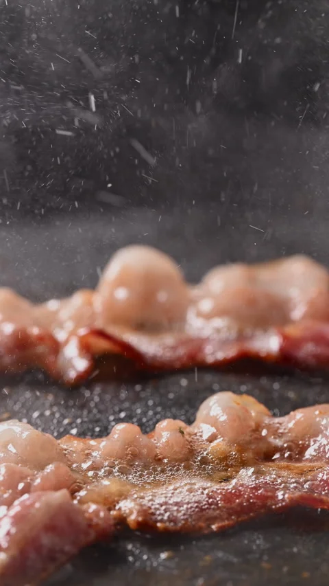 Crispy bacon sizzling in a pan, close-up shot. 動画素材 317453335