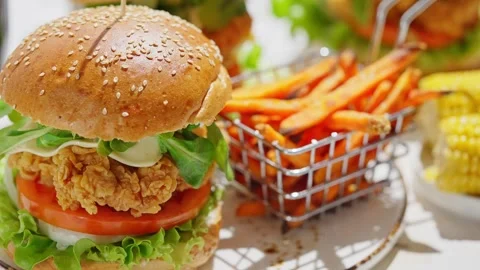 Crispy, breaded chicken double burgers with vegetables and drink, served with Stock Footage 250158207