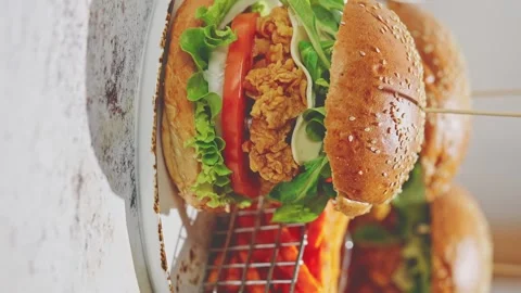 Crispy, breaded chicken double burgers with vegetables and drink, served with Stock Footage 254679345