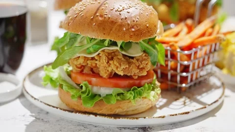 Crispy, breaded chicken double burgers with vegetables and drink, served with Stock Footage 254679559