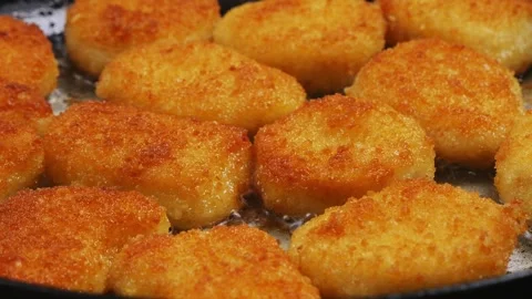 Crispy breaded chicken nuggets are fried in a frying pan Stock Footage 296550158