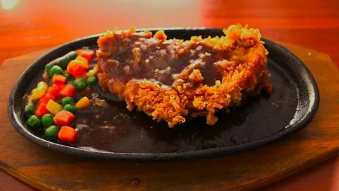 Crispy breaded chicken steak served on a hot hotplate Stock-Fotos