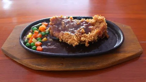 Crispy breaded chicken steak served on a hot hotplate Foto stock