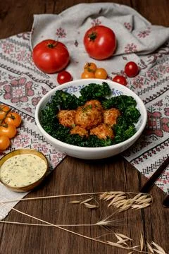 Crispy breaded meatballs with a side of greens and gravy Stock Photos