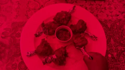 Crispy chicken lollipop platter with dipping sauce under vibrant red restaurant Vídeos de archivo 334664056