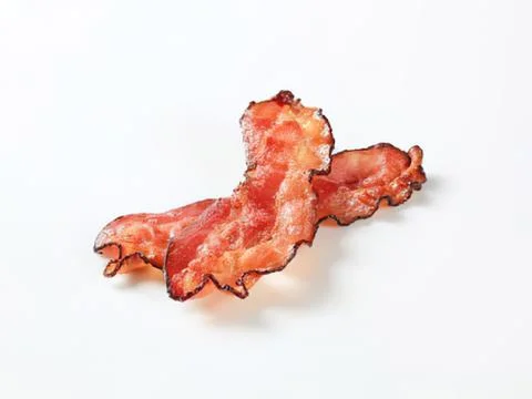 Crispy cooked bacon pieces on plain background Stock Photos