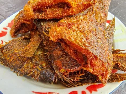 Crispy Deep Fried Tilapia Fish Served on a Traditional Patterned Plate Stockfoto's