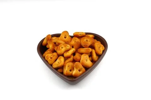 Crispy, flavorful triangular chips in a heart-shaped bowl against a wooden .. Stock Photos