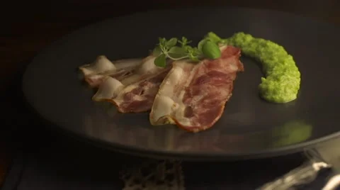 Crispy fried bacon on black plate with  pouring sauce Stock Footage 57381412