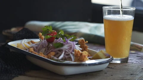 Crispy Fried Calamari with Fresh Peruvian Ceviche and Pouring Beer Stock Footage 338341179