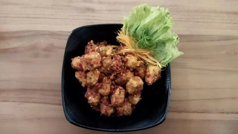 Crispy fried chicken bites served on a black plate with fresh lettuce garnish Stock Photos