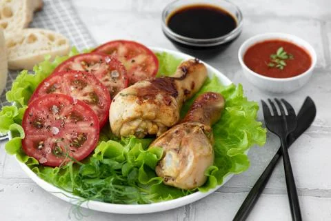Crispy fried chicken drumsticks with fresh tomatoes and lettuce Stock Photos
