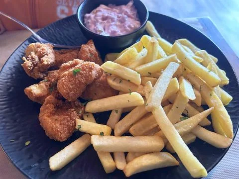 Crispy fried chicken nuggets bites, French fries, creamy dipping sauce on plate Foto stock