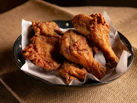 Crispy Fried Chicken Pieces on Rustic Plate with Burlap Cloth, Comfort Food Stockfoto's