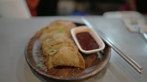 Crispy fried dumplings served with dipping sauce on a wooden plate at El Nido Stockbeeldmateriaal 309498622