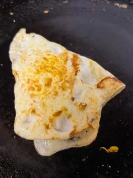 Crispy fried egg square folded on hot black cooking pan close up Fotos de archivo