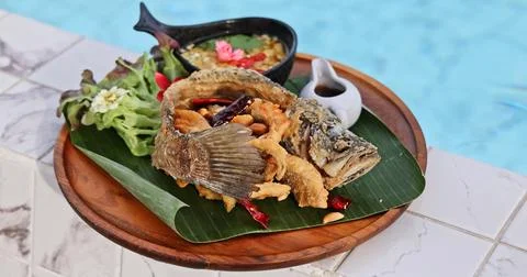 Crispy Fried Fish by Pool - Luxury Tropical Dining Foto stock
