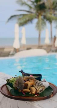 Crispy fried fish served by poolside with ocean view, tropical setting Stock Photos