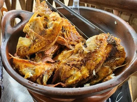 Crispy fried fish served rustic clay pot. Stock Photos