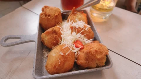 Crispy fried food balls served in a small metal dish topped with grated cheese. 库存影片 343402439