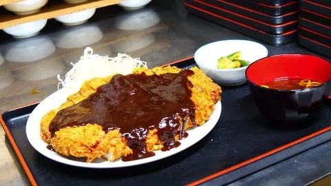 Crispy fried pork cutlet covered with rich brown sauce on white plate Fotos de archivo