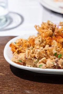 Crispy fried squid tentacles served on a plate with a lemon wedge in a rest.. Photos