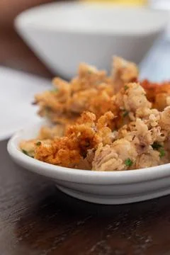 Crispy fried squid tentacles served on a plate with a lemon wedge in a rest.. Фото