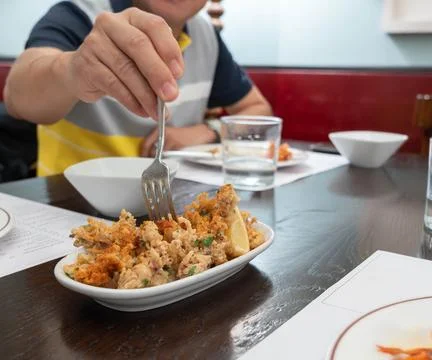 Crispy fried squid tentacles served on a plate with a lemon wedge in a rest.. Fotos Stock
