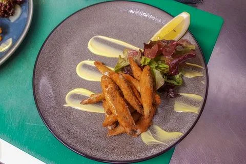 Crispy fried whitebait served with fresh salad and lemon slice on a plate Stock Photos