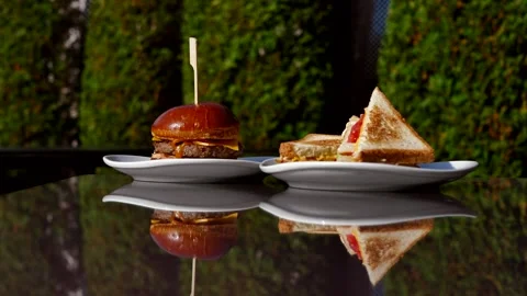 Crispy grilled beef burger and delicious ham sandwich on a glass table. Stock Footage 287480693
