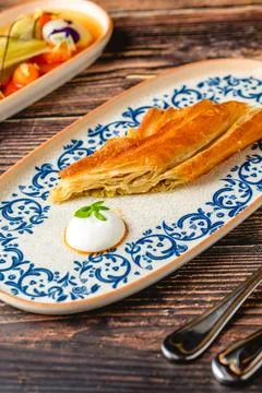 Crispy layered Turkish borek slice with yogurt dip Stock Photos