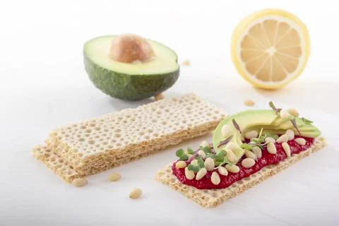 Crispy low calorie wheat crackers with beetroot hummus, pine nuts and avocado Stock Photos