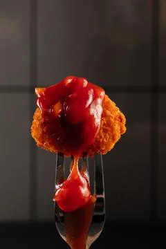 A crispy nugget is pierced on a fork. Stock Photos