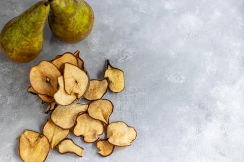 Crispy pear fruit chips on a gray background. In the background are ripe pear Foto stock