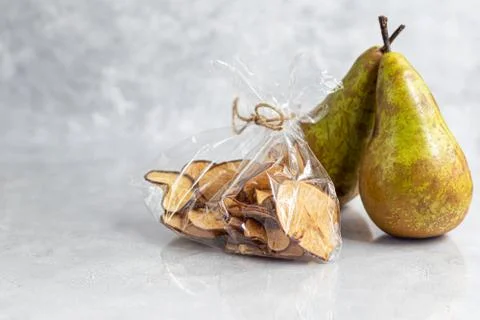 Crispy pear fruit chips on a gray background. In the background are ripe pear Фото