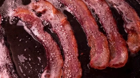 Crispy pieces of tasty thin smokey bacon fried in a hot skillet. 스톡 동영상 334643175