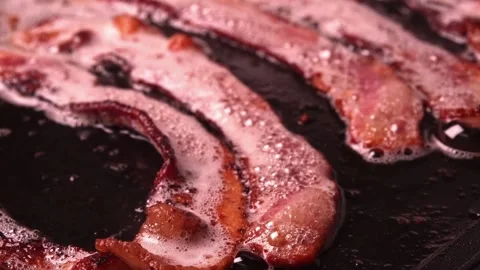 Crispy pieces of tasty thin smokey bacon fried in a hot skillet. 스톡 동영상 334643178