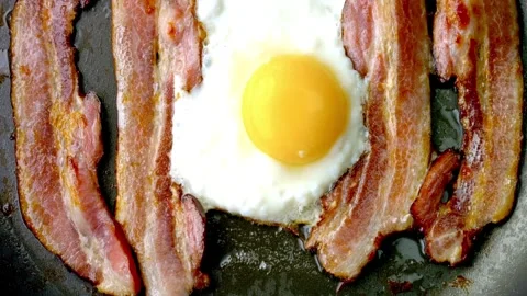 Crispy pork bacon and egg being cooked with Splashes of sizzling oil. 스톡 동영상 334643415