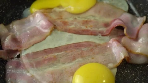 Crispy pork bacon and egg being cooked with Splashes of sizzling oil. 스톡 동영상 334643433
