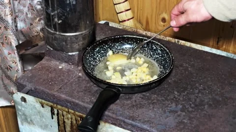 Crispy pork fat sizzling and frying in pan on cast iron wood stove Stock Footage 336010314