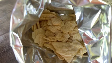 Crispy potato chips inside shiny foil package with crunchy snack texture and Stock Footage 345720656