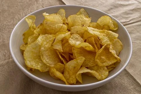 Crispy potato chips piled high in a white bowl. Stock Photos