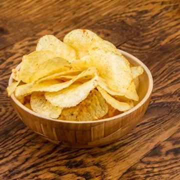 Crispy potato chips in a wicker bowl on old kitchen table Generative AI Foto stock